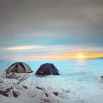 black tent on snow covered ground during sunset